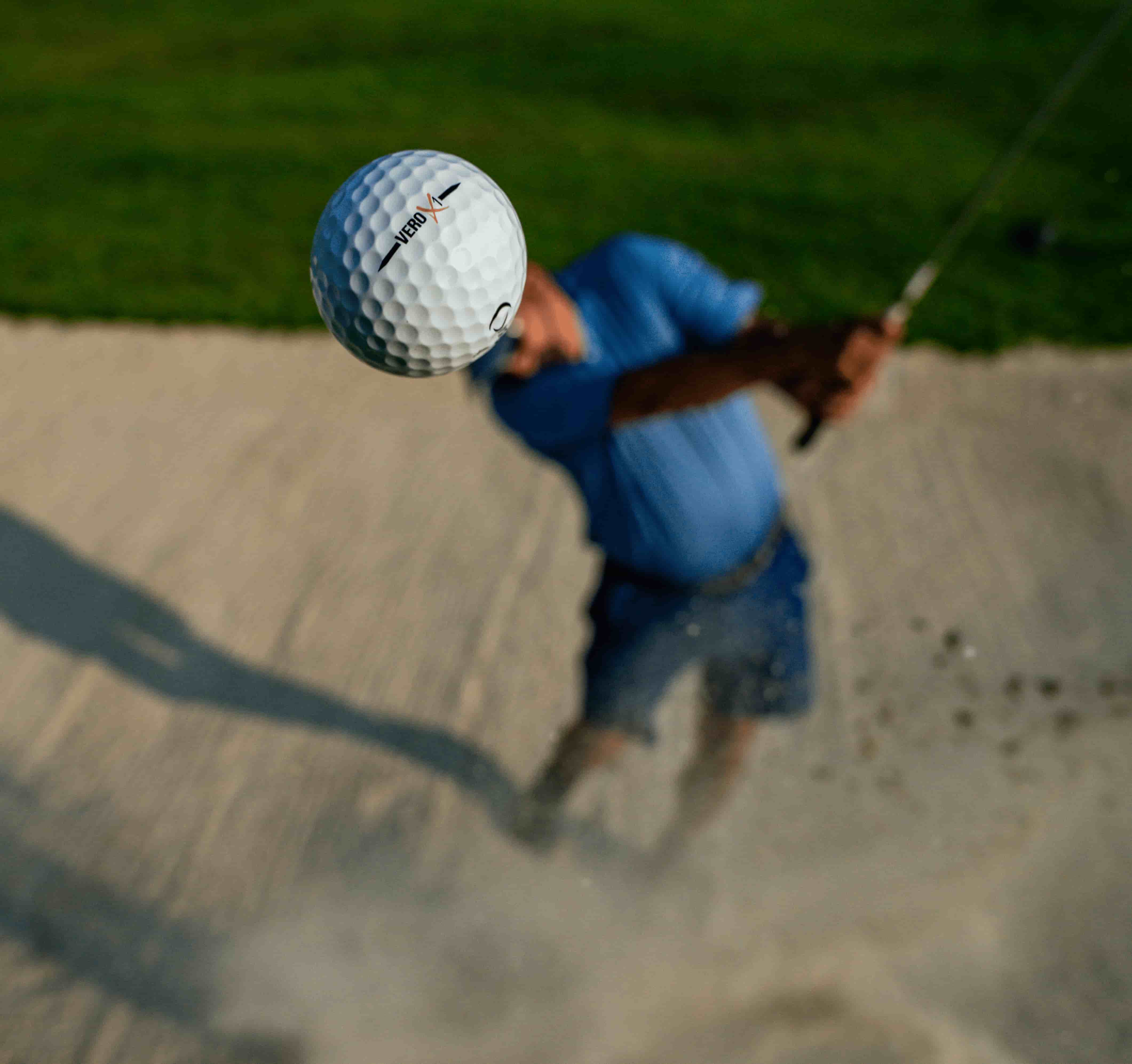 A golfer hitting a ball out of a sand bunker