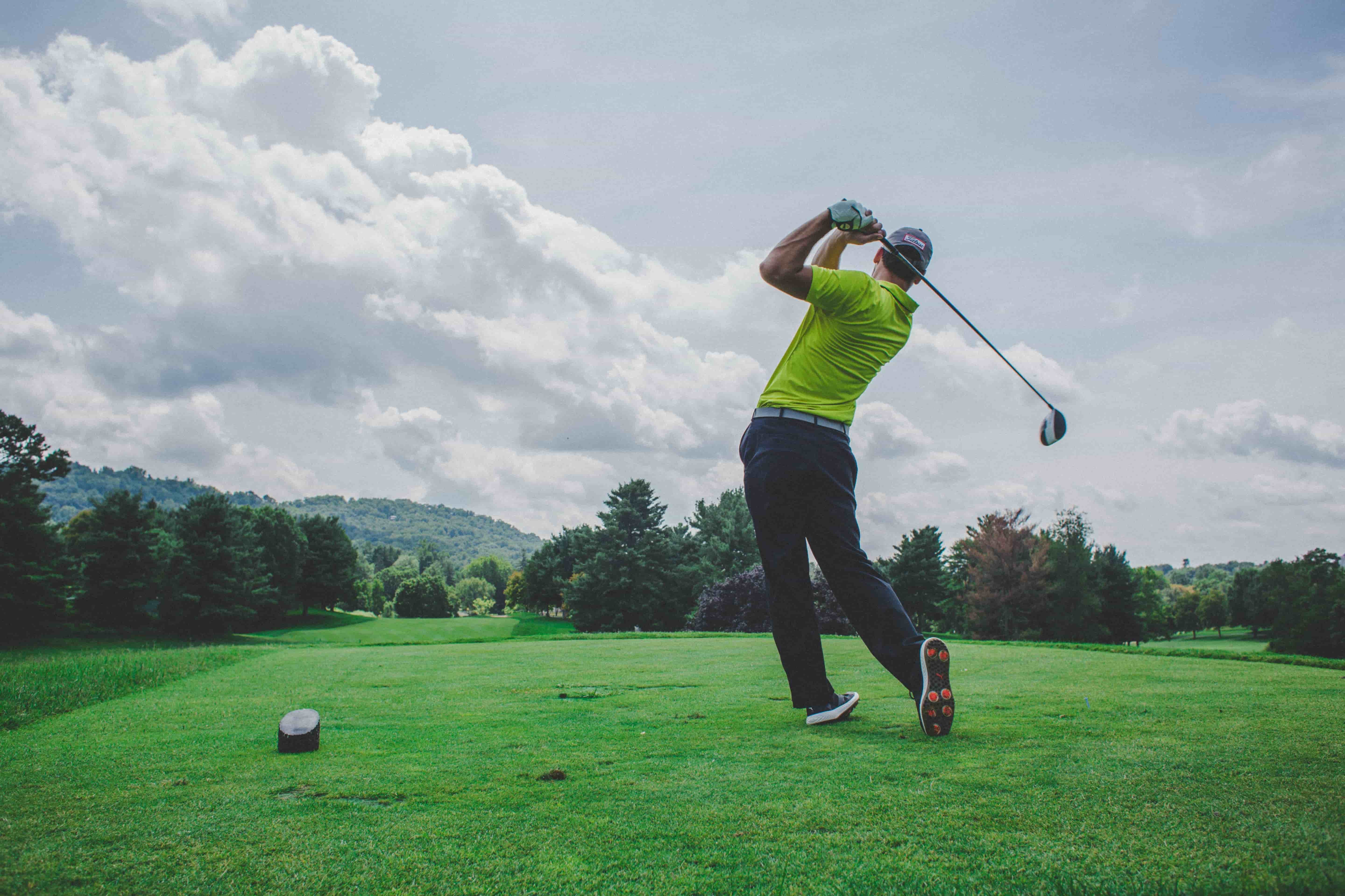 A golfer at the end of their swing on a golf course